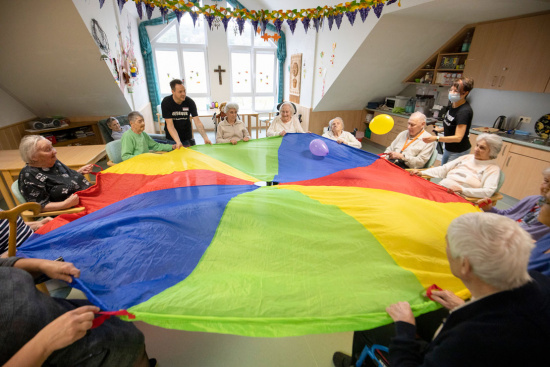 Zwei Betreuer spielen mit Seniorinnen und Senioren