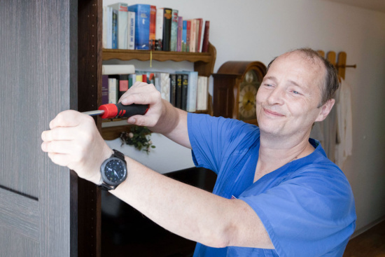 Ein lachender Mann mit einem Schraubenzieher