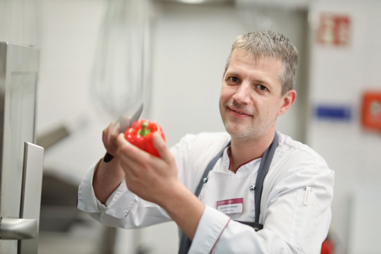 Ein Koch schneidet eine rote Paprika