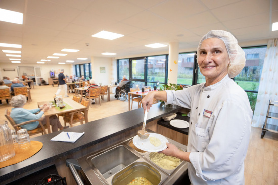 Eine Küchenkraft füllt Essen auf ein Teller