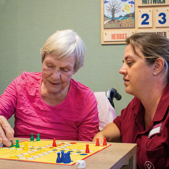 Mitarbeiterin und Bewohnerin beim Brettspiel