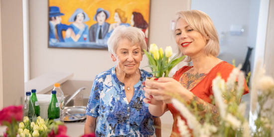 Eine Betreuerin bindet einen Blumenstrauß mit einer Bewohnerin